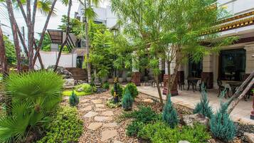 A courtyard with a stone pathway, tropical plants, and outdoor furniture.