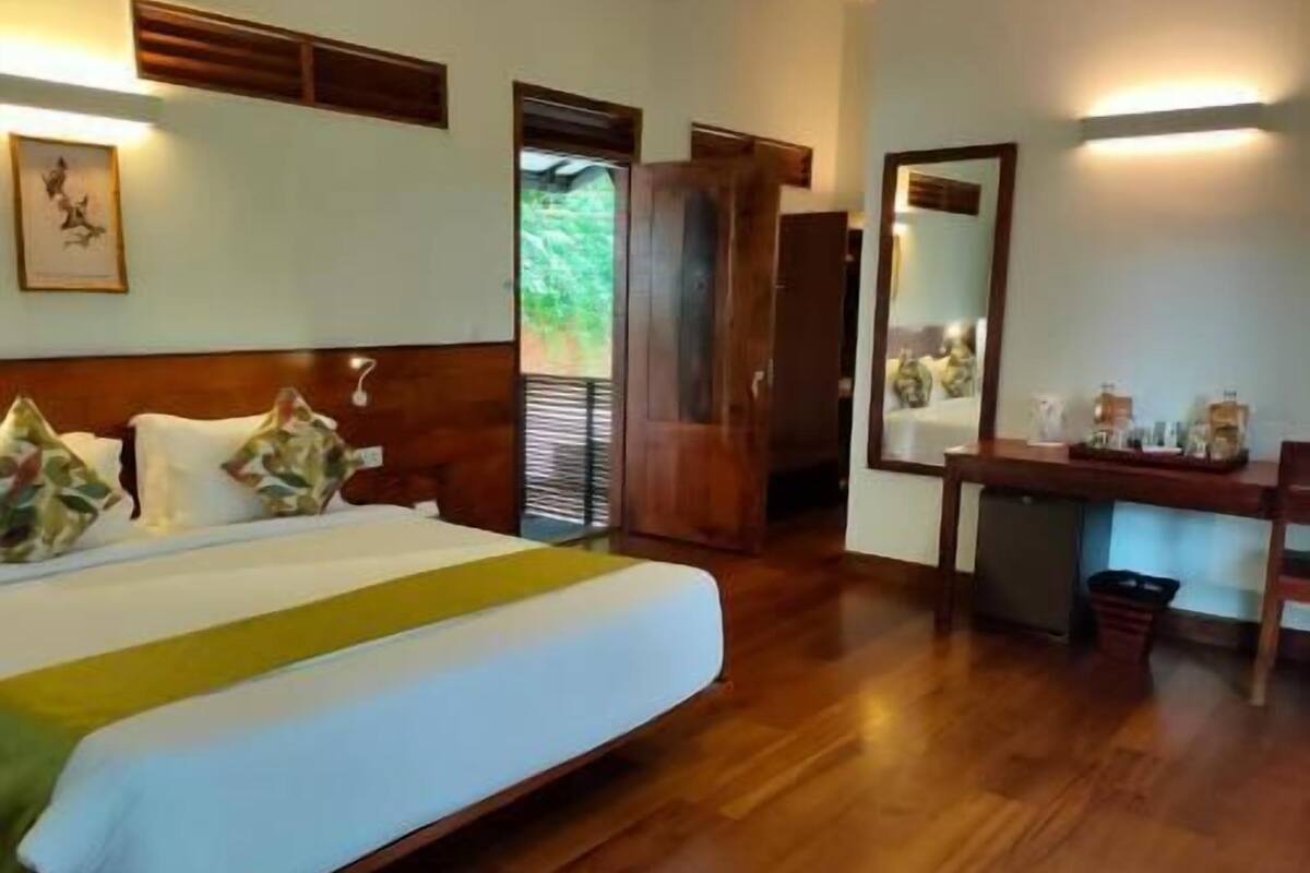 Une chambre d’hôtel avec un lit en bois, un bureau et un miroir.
