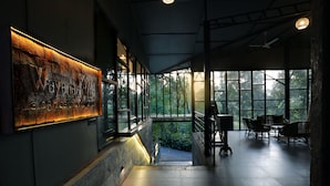 Een modern interieur met een stenen muur, een trap die naar een balkon leidt, en uitzicht op groen.