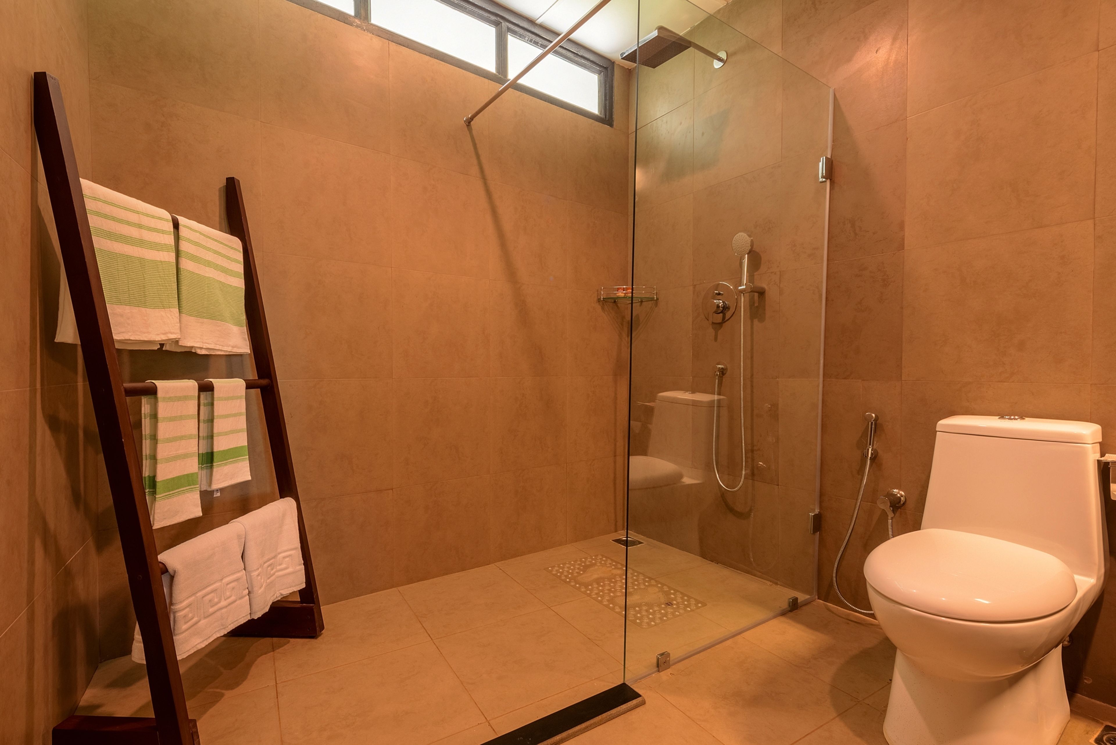 Un baño moderno con cabina de ducha de vidrio, inodoro y toallero con toallas a rayas.