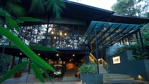 Een modern gebouw met een glazen gevel, een terras en een trap naar de ingang.