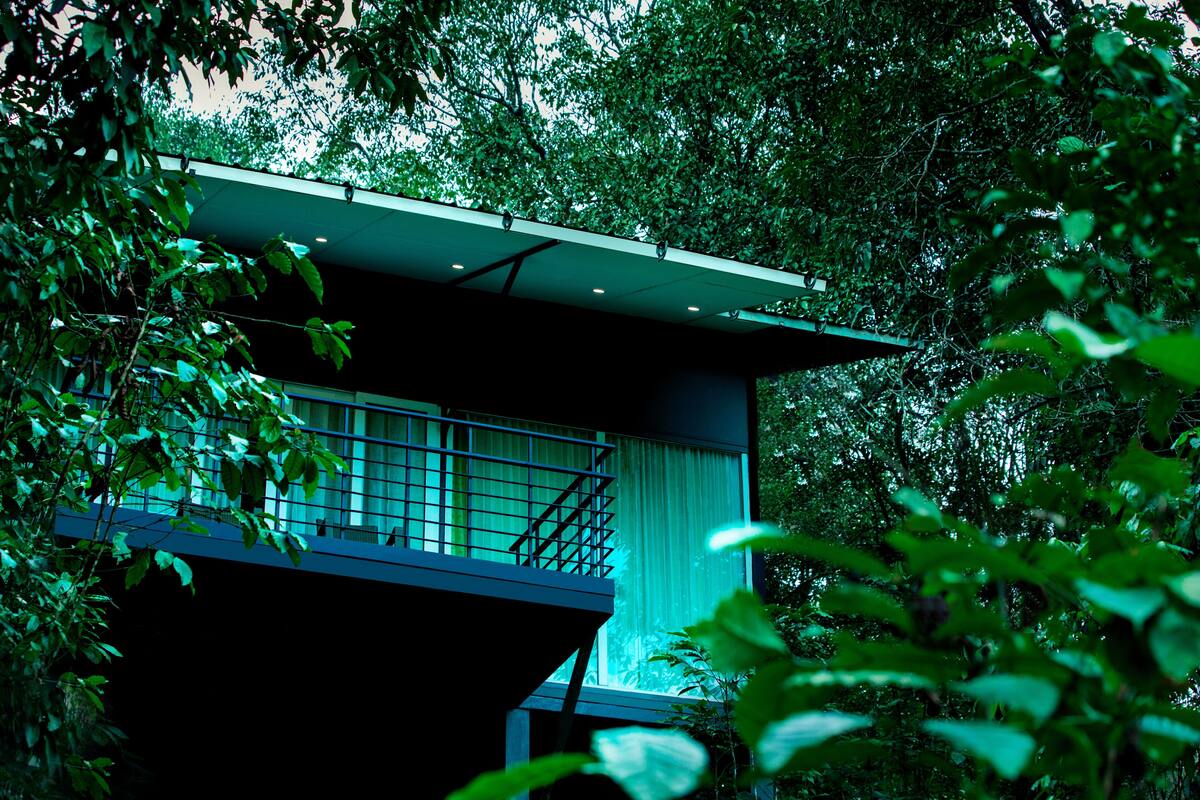 Un bâtiment moderne doté d’un balcon, entouré d’une végétation luxuriante.