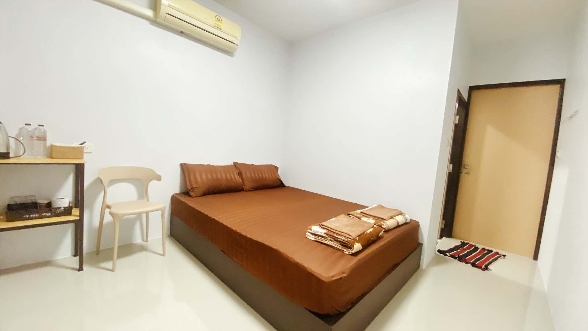A bedroom with a bed, a desk, a chair, and a wardrobe.