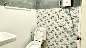 A bathroom with a toilet, a sink, and a shower unit. - Ploynam Homestay (Amphawa)