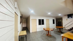 A spacious interior with a central round table, two smaller tables, and a staircase leading to an upper level. - Ploynam Homestay (Amphawa)