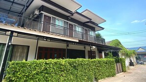 A modern two-story house with a balcony, large windows, and a well-maintained hedge. - Ploynam Homestay (Amphawa)