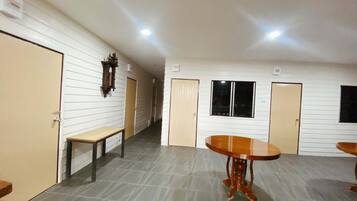 A hallway with a wooden bench, a round table, and doors leading to individual rooms.