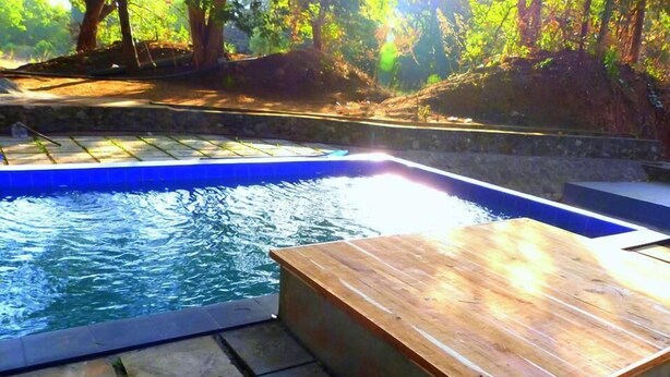 Una piscina con muelle de madera y escalones de piedra para entrar.