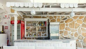 A bar area with a stone wall, a refrigerator, and a shelf with bottles. - New Bodrum Hotel (Bodrum)