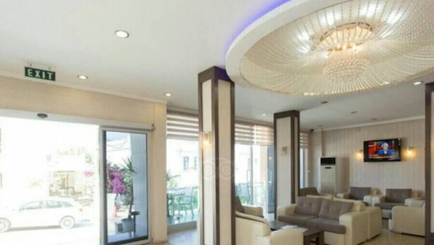 A hotel lobby with a reception area, seating, and a large chandelier. - New Bodrum Hotel (Bodrum)