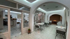 A spacious dining area with high ceilings and a modern design, featuring multiple tables and chairs arranged for dining.