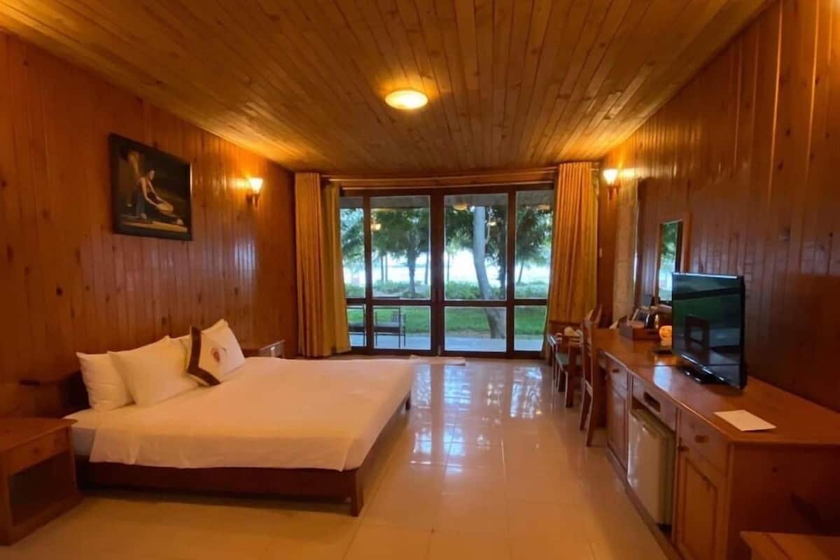 A wooden cabin with a bed, a TV, and a kitchen area.