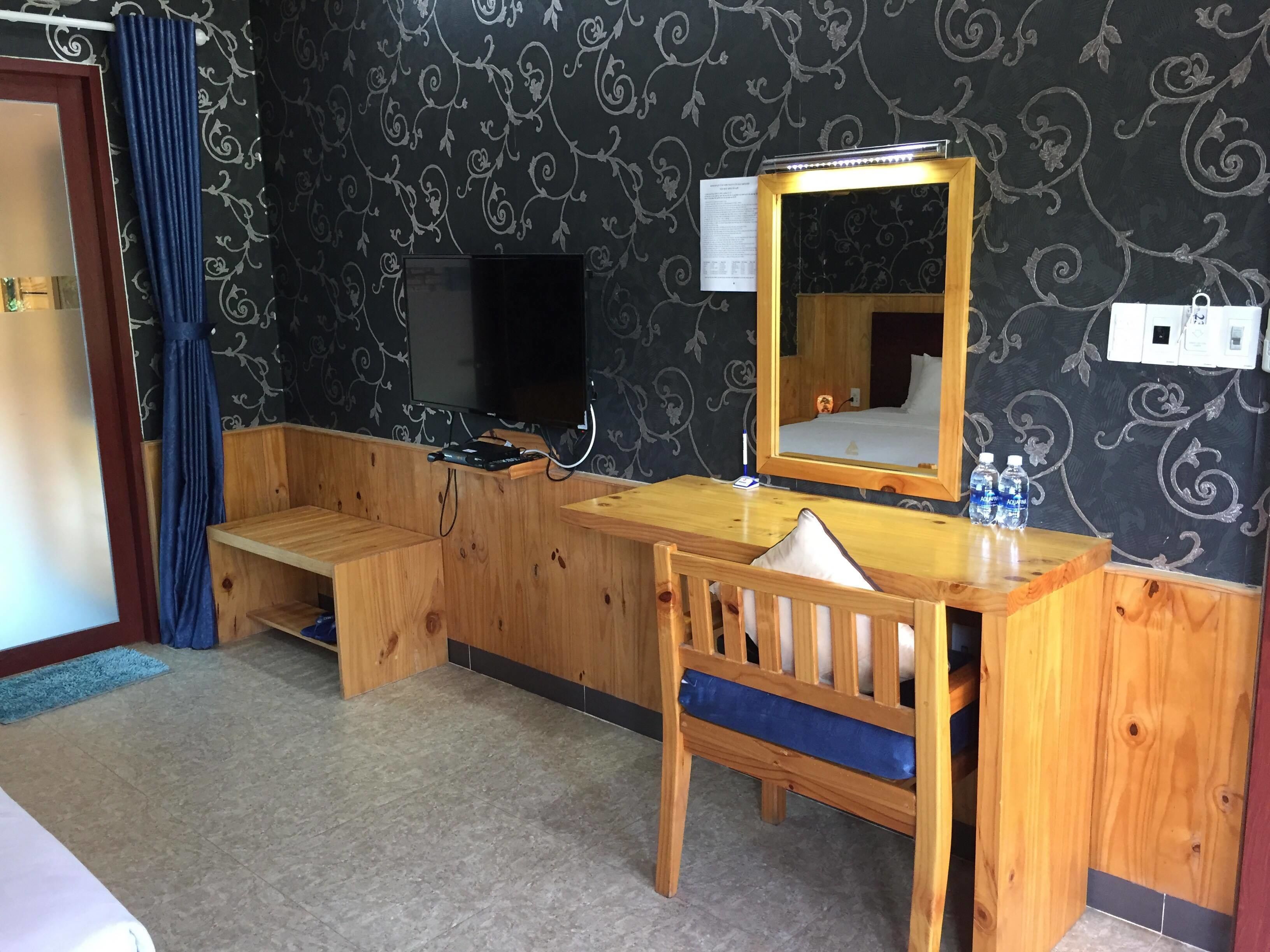 Un escritorio de madera con un espejo, un televisor y un banco.