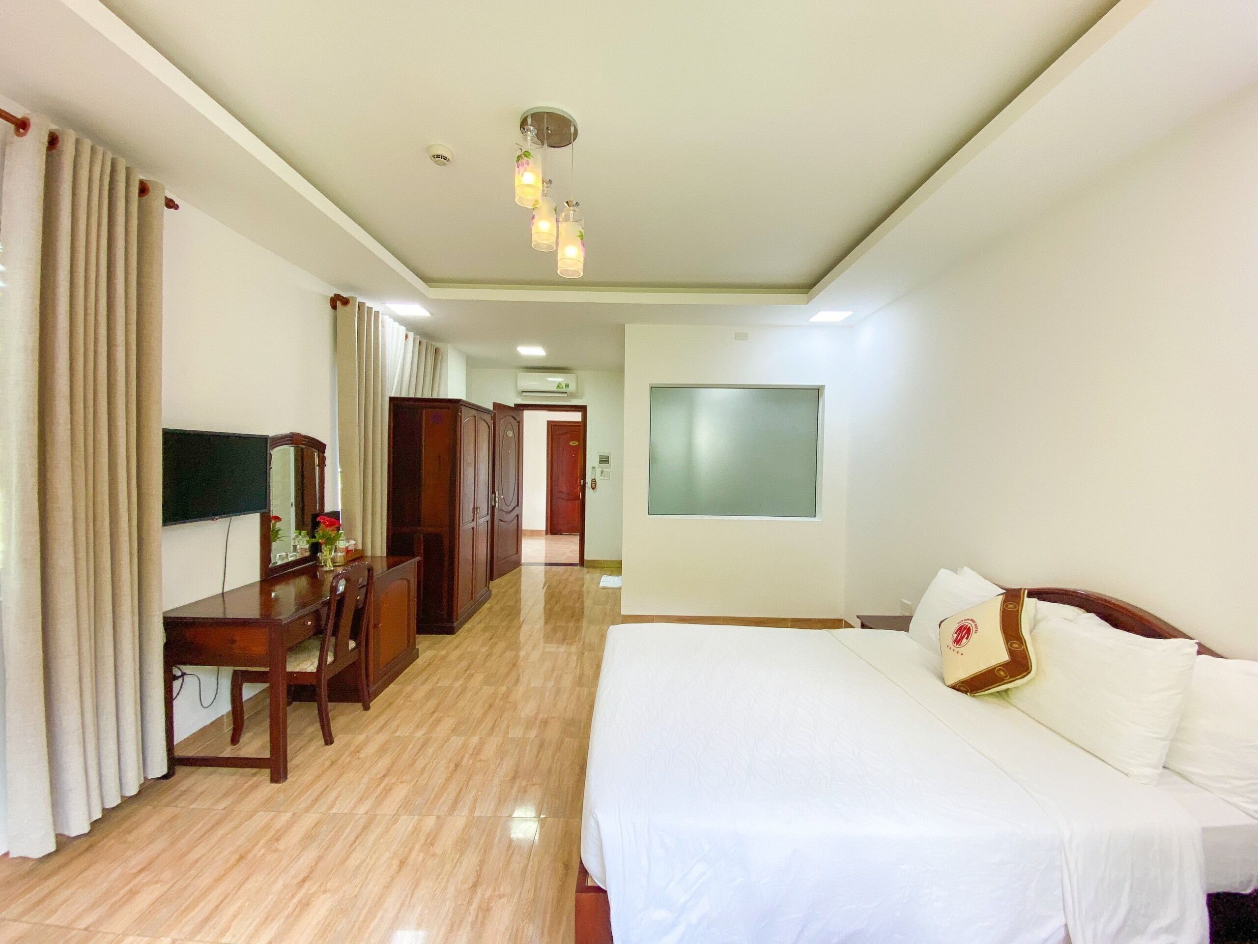 A hotel room with a bed, a desk, a chair, a TV, and a wardrobe.