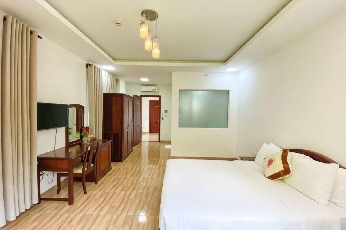 Une chambre d’hôtel comprenant un lit, un bureau, une chaise, un miroir et une armoire.