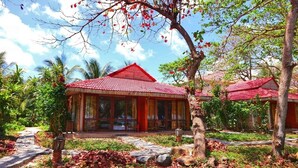 A traditional-style building with a red roof, surrounded by lush greenery and palm trees. - Tan Son Nhat Con Dao Resort (Ho Chi Minh City)