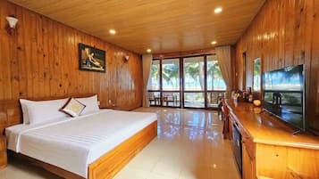 Habitación con paneles de madera, una cama, un televisor y vistas a la playa.