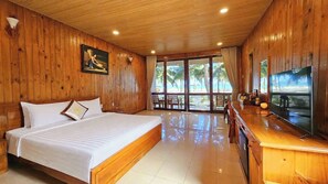 A wooden-paneled room with a bed, a television, and a view of the beach. - Tan Son Nhat Con Dao Resort (Ho Chi Minh City)