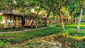 A traditional bungalow with a tiled roof, surrounded by lush greenery and palm trees. - Tan Son Nhat Con Dao Resort (Ho Chi Minh City)