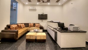 Una sala de estar moderna con un sofá seccional, una mesa de centro, un escritorio con una computadora y un televisor de pantalla plana montado en la pared.