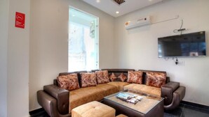 Una sala de estar moderna con un sofá modular, una mesa de centro de vidrio y un televisor de pantalla plana montado en la pared.