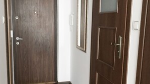 Un corridoio con una porta in legno, uno specchio e un tappetino all'ingresso.