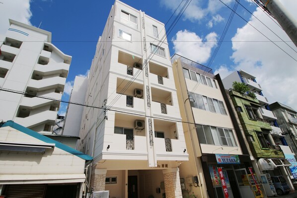 A multi-story building with balconies, air conditioning units, and a storefront with signage. - Condominium Felicita Naha (Naha)