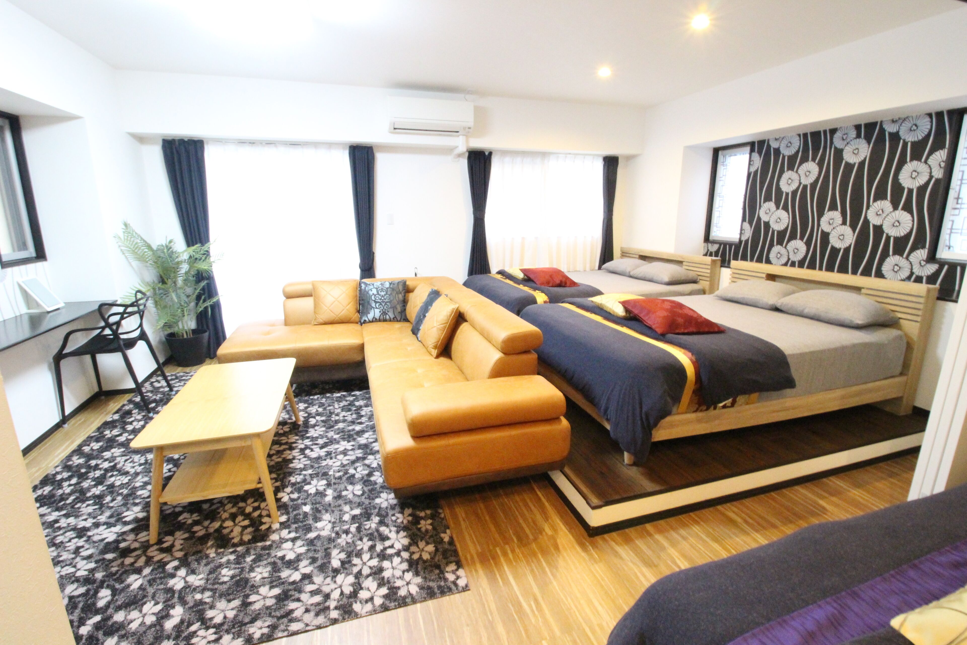 A modern hotel room with a sofa, a bed, a small table, and a potted plant.
