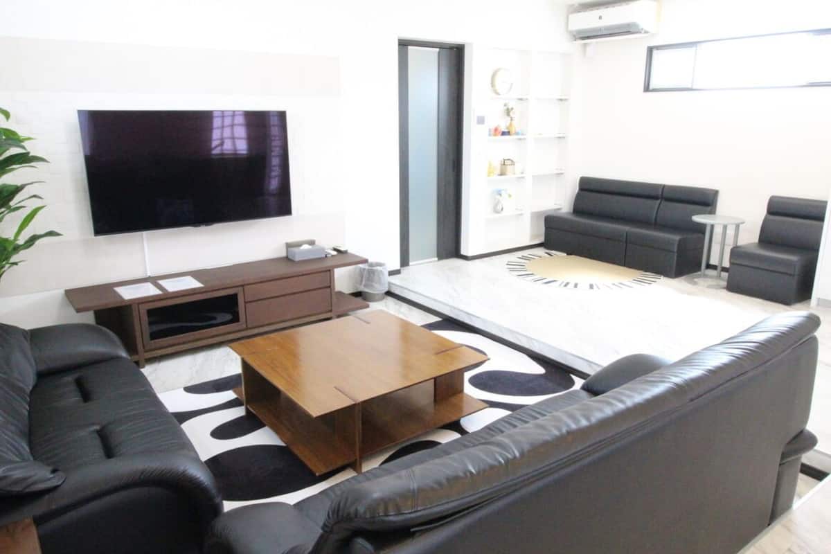 Un salon moderne avec un téléviseur à écran plat, un canapé, une table basse et un tapis à motifs.
