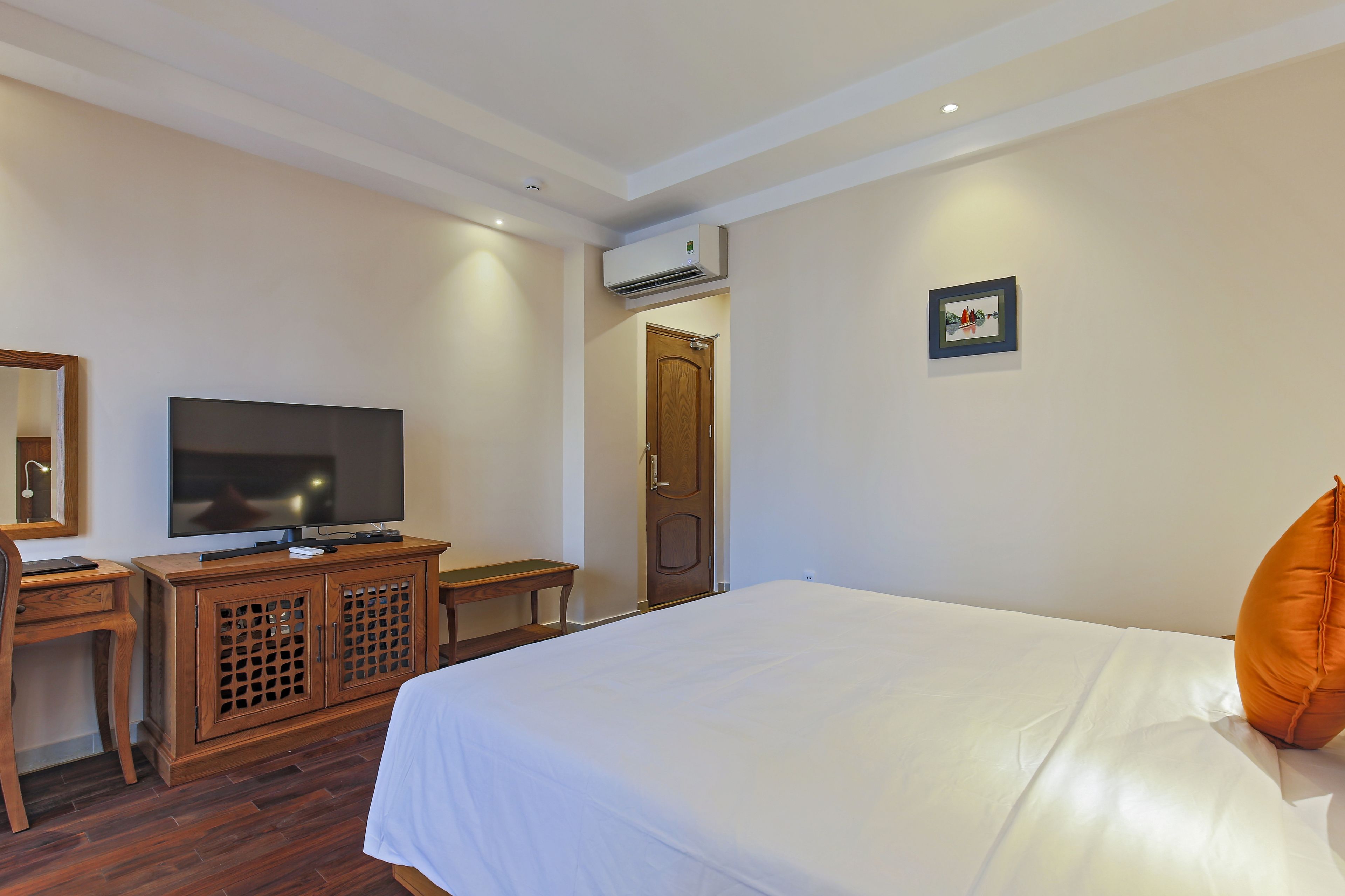 A hotel room with a bed, a television, a wooden cabinet, and a door.