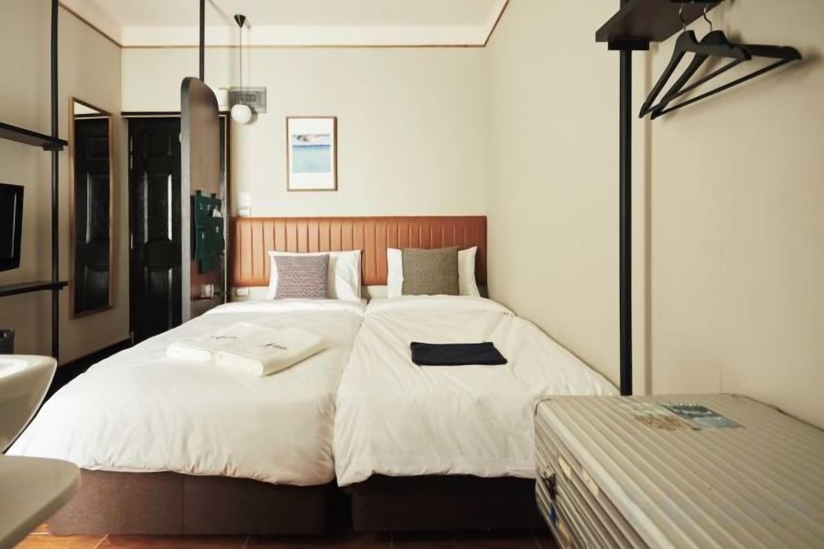 Ein Hotelzimmer mit zwei Betten, einem Schreibtisch und einem Sessel.