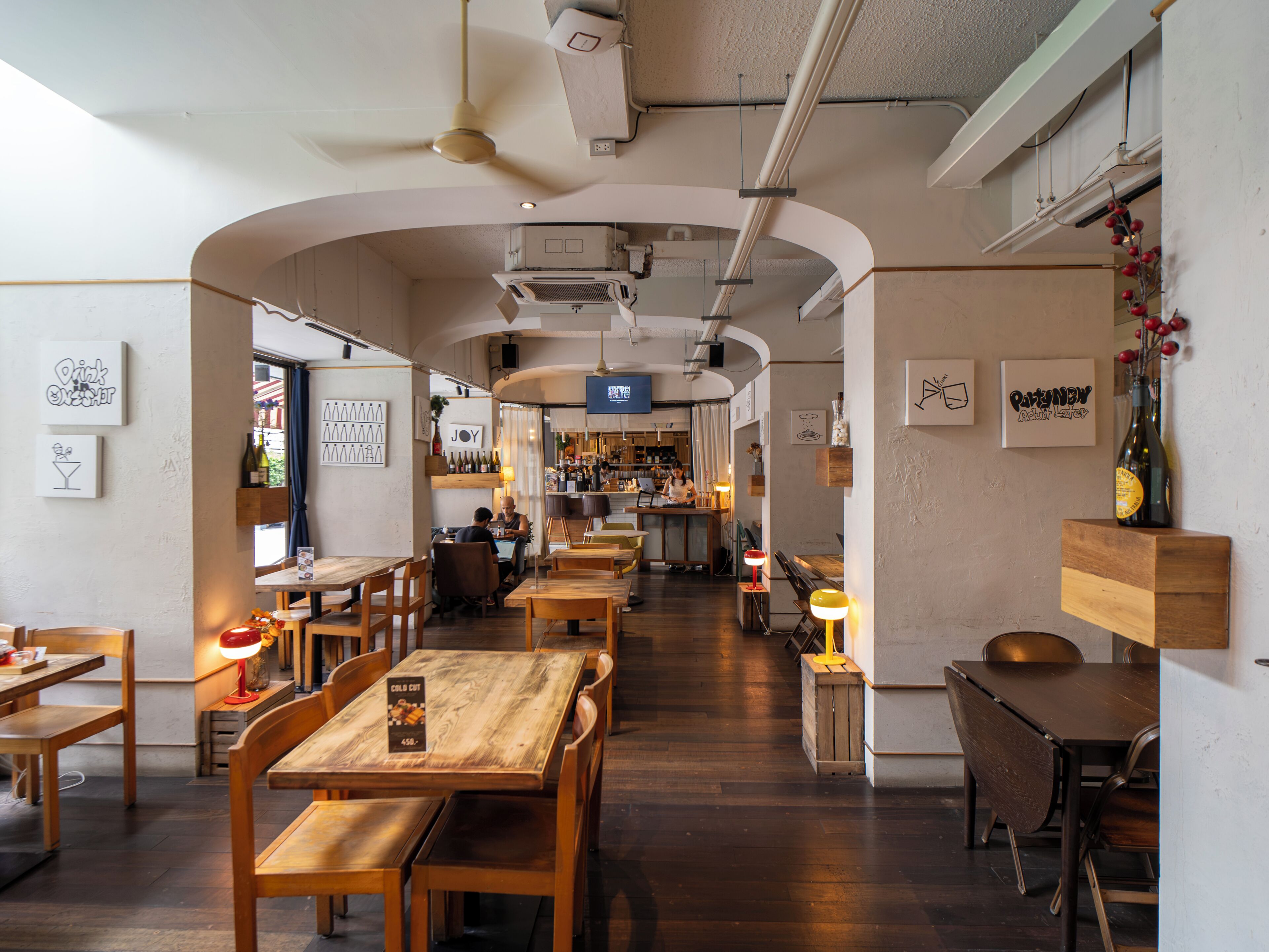 A restaurant interior with wooden tables and chairs, a bar area, and artwork on the walls.