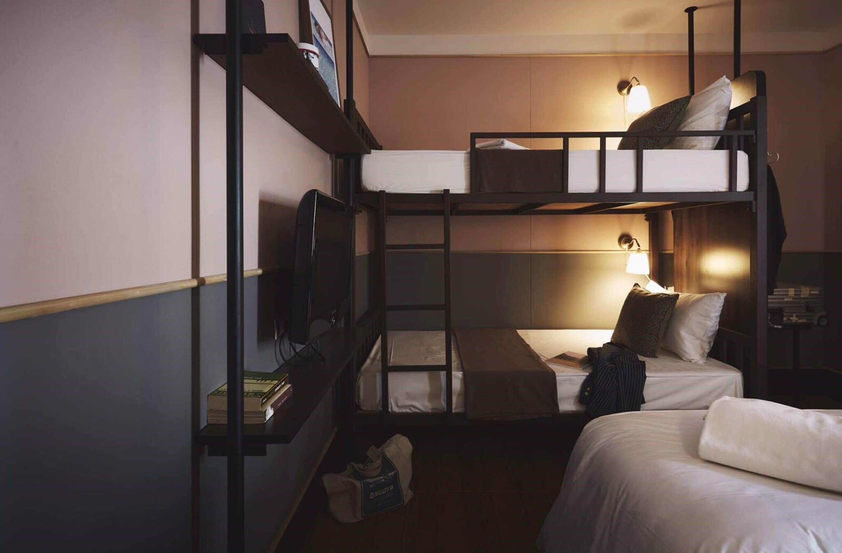 A bunk bed room with a TV, a desk, and a lamp.