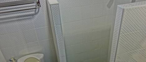 A bathroom with a toilet, a shower, and a towel rack.