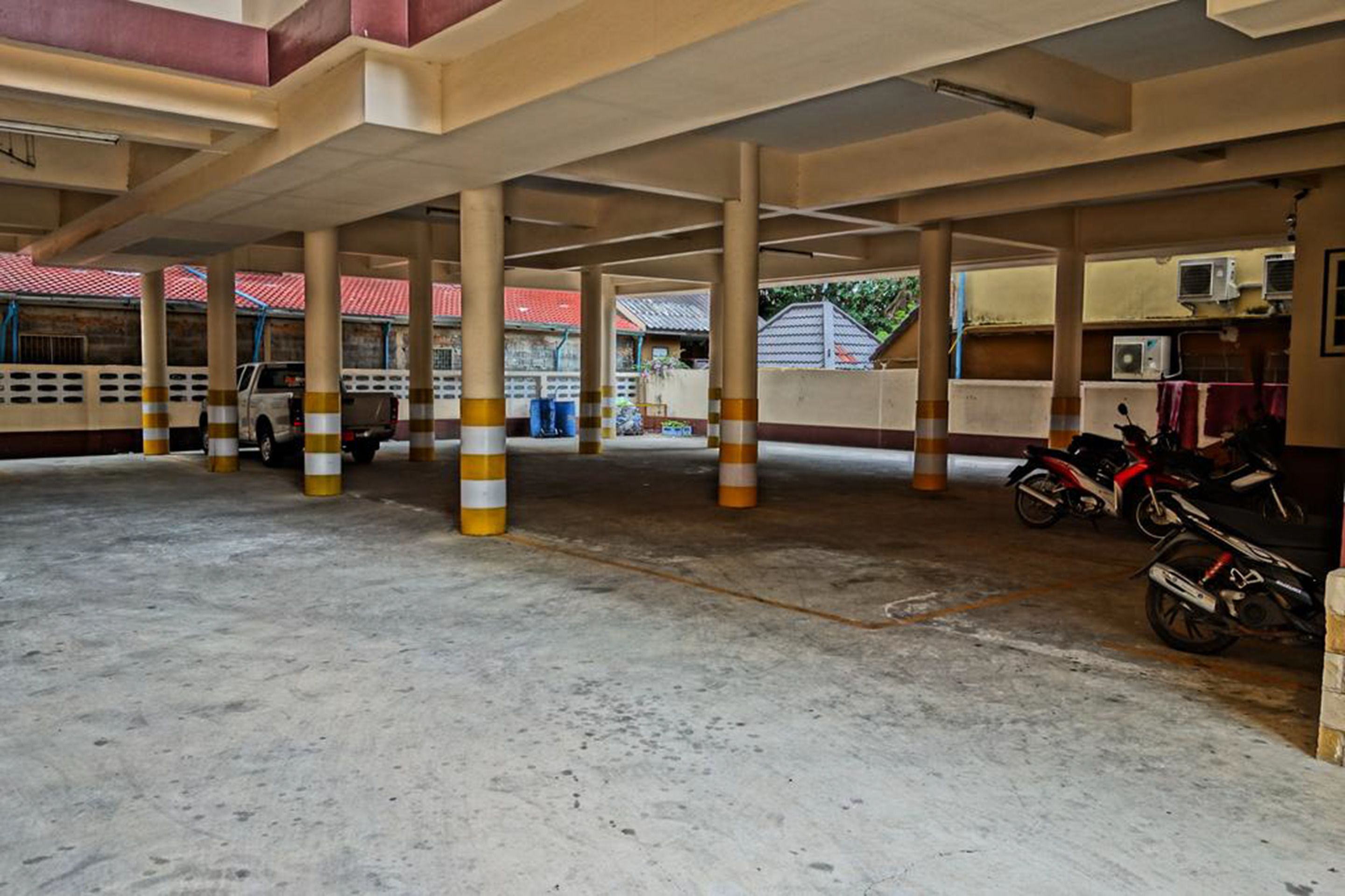 Un estacionamiento techado con pilares de hormigón y una motocicleta estacionada a un lado.
