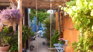 Uma área externa coberta com balanço, plantas em vasos e uma cadeira azul.