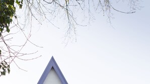 Uma casa branca com detalhes azuis e telhado em forma de mansarda.