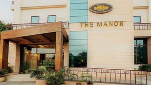 A hotel entrance with a sign reading "THE MANOR" and a logo above it.