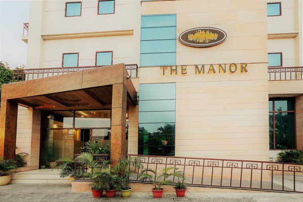 A hotel entrance with a sign reading "THE MANOR" and a logo above it.