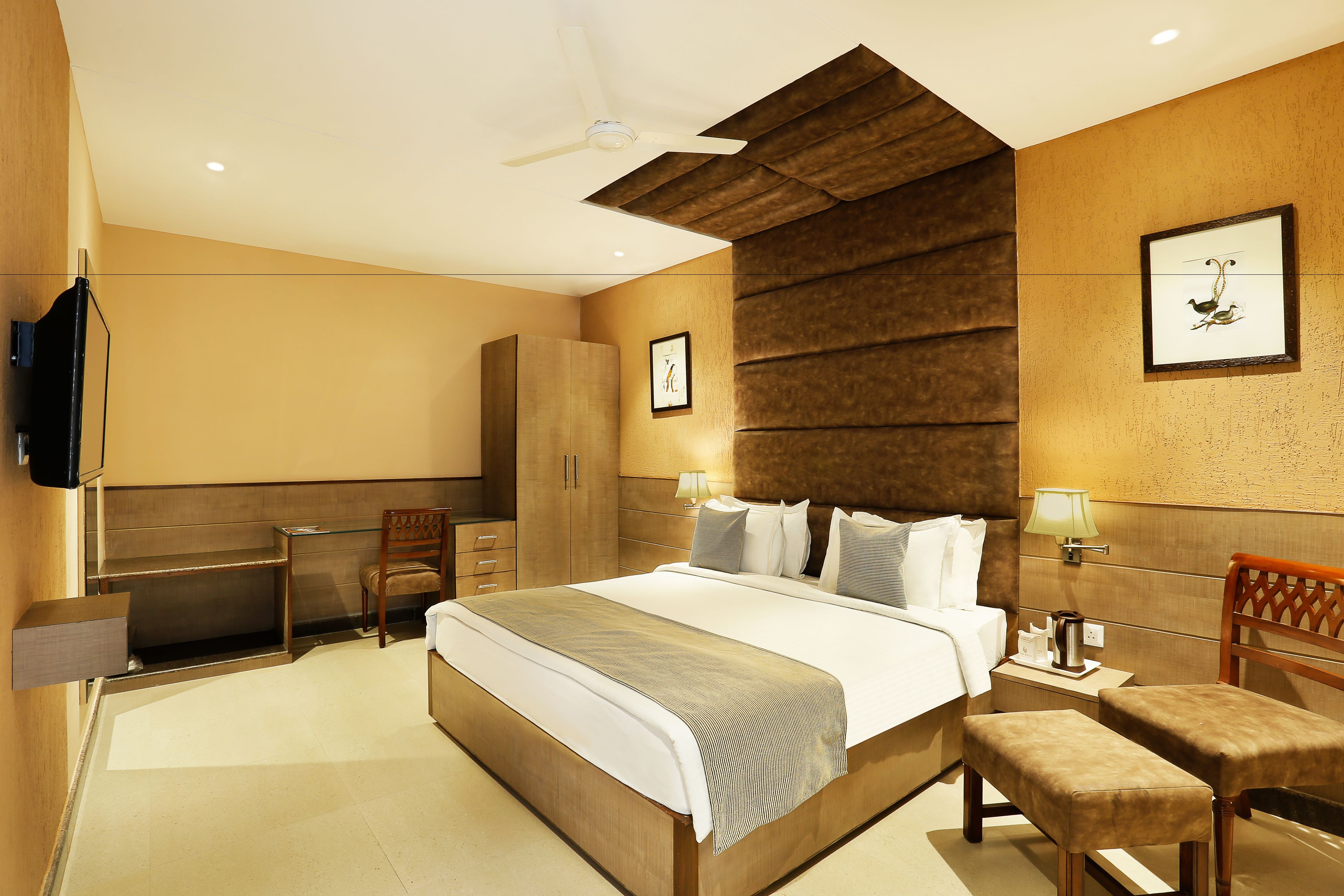 A modern hotel room with a large bed, a desk, a chair, and a TV.