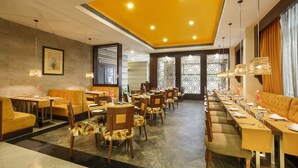 A restaurant with a long table, chairs, and a yellow ceiling.