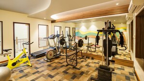 A gym with exercise equipment, a treadmill, and a mirrored wall.