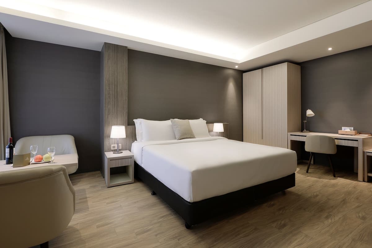 Una habitación de hotel moderna con una cama grande, mesitas de noche, un escritorio y una silla.
