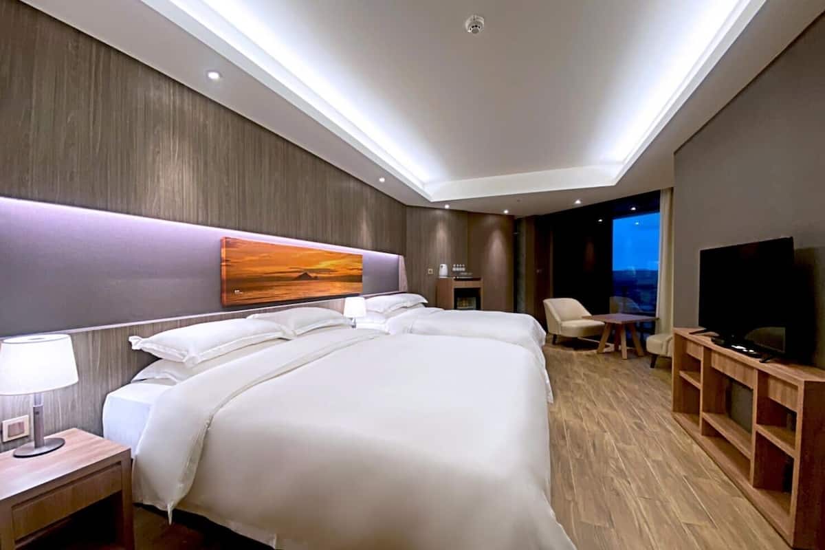 Una habitación de hotel moderna con una cama grande, televisor, escritorio y una silla.