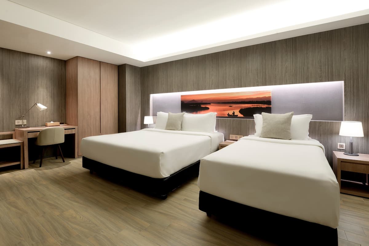 Habitación de hotel con dos camas, un escritorio y una silla.