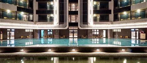 Interior moderno de hotel con piscina central, varios pisos y diseño simétrico.