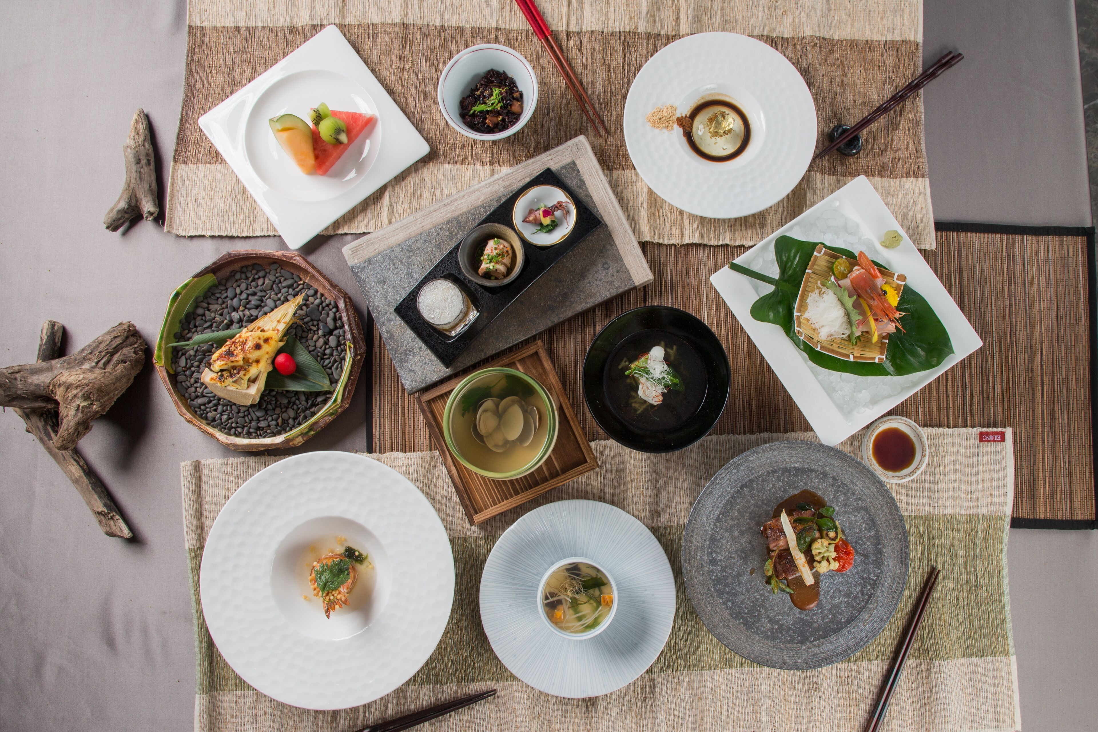 Variedad de platos y tazones dispuestos sobre una mesa con palillos y un posavasos.
