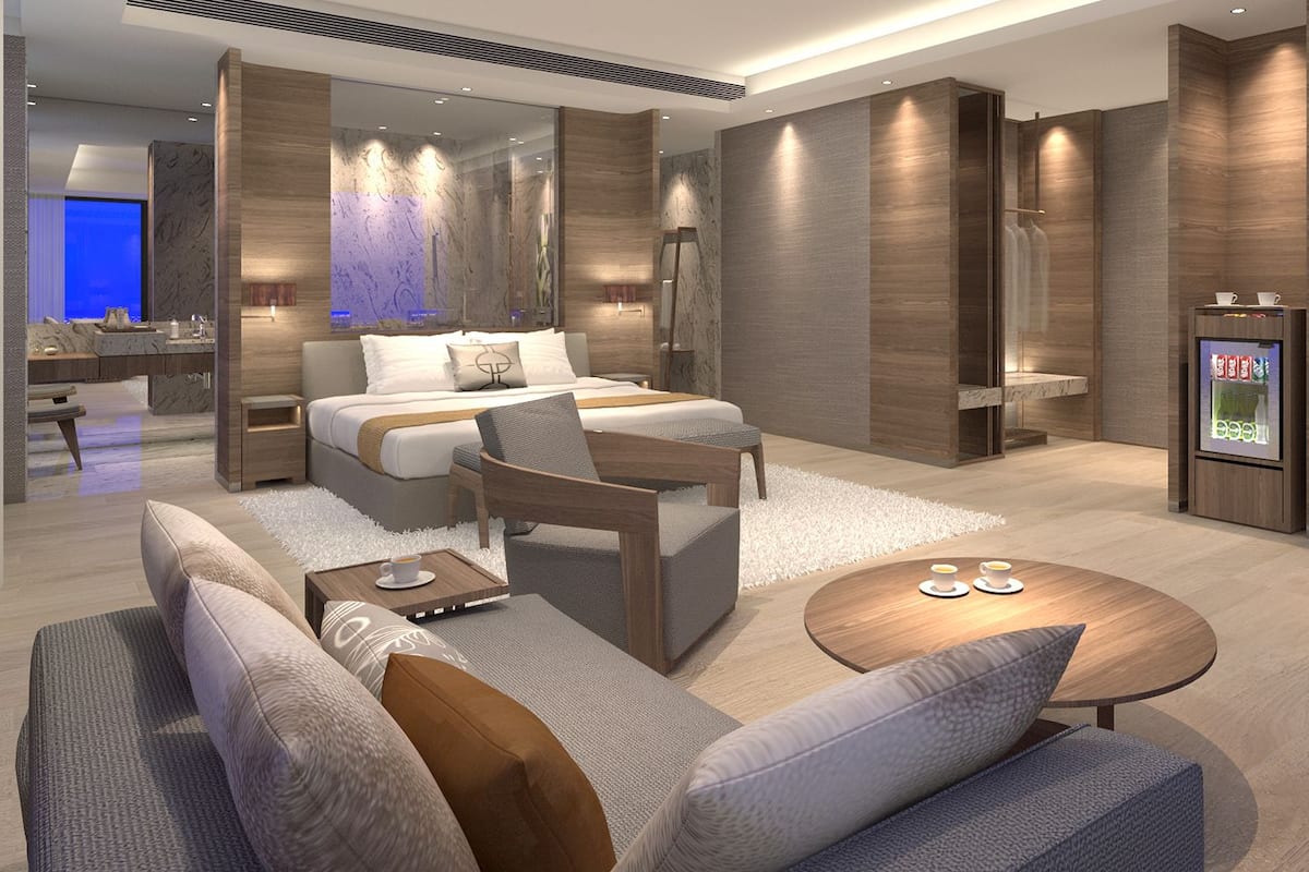 Una habitación de hotel moderna con una cama grande, un sofá, una mesita de centro y un televisor.