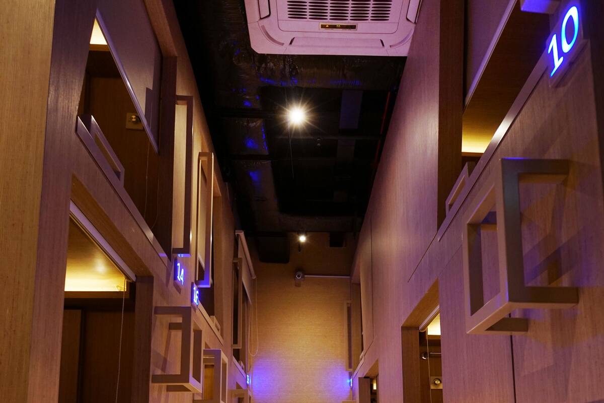 A hotel corridor with wooden walls, numbered rooms, and a patterned carpet.