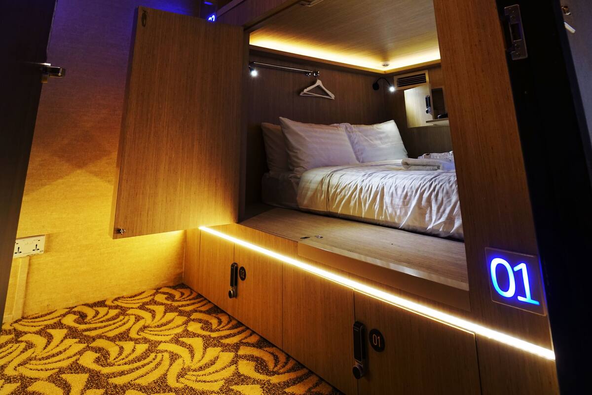 A compact, well-lit room with a bunk bed, a small desk, and a hanging garment rack.